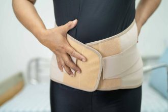 Femme asiatique portant un correcteur de posture pour soulager des douleurs au dos