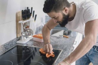 Jeune homme nettoyant une plaque vitrocéramique avec des produits naturels